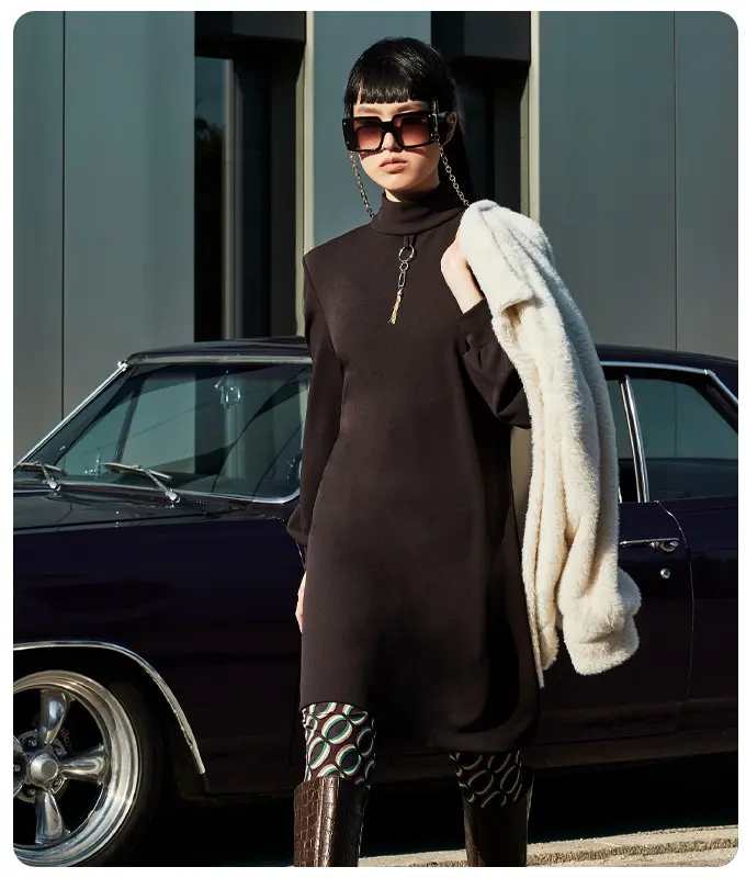 Ana Alcazar Model trägt Braunes Rollkragenkleid mit Retroprint Leggings und weißer Jacke